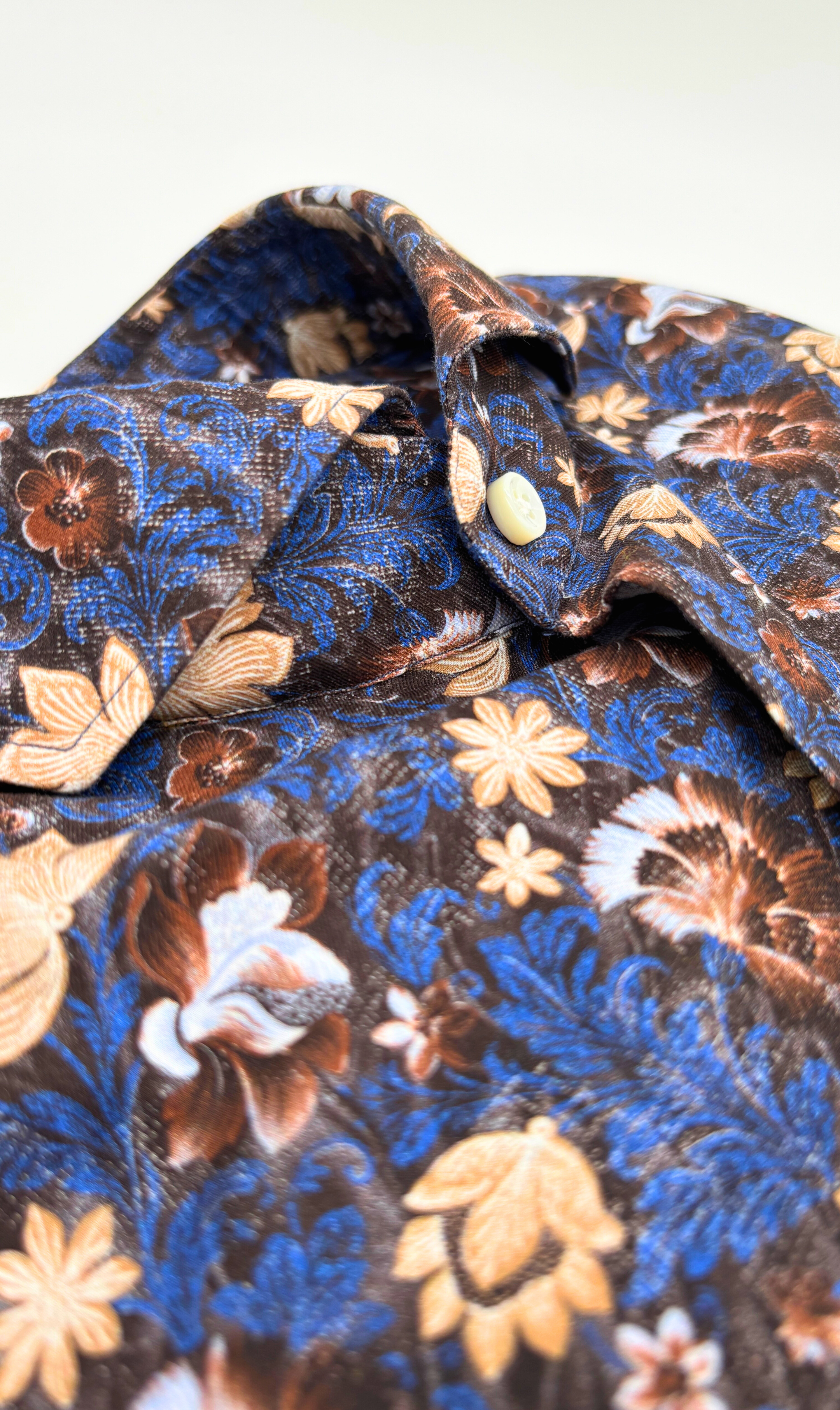 Detailansicht des Softcollar-Kragens und der runden Manschetten des nachhaltigen Herrenhemds mit braunen blumen-Muster.